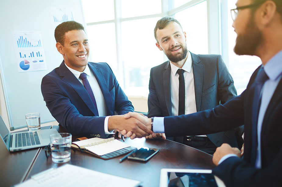 Two office workers shake hand with their SEO client.