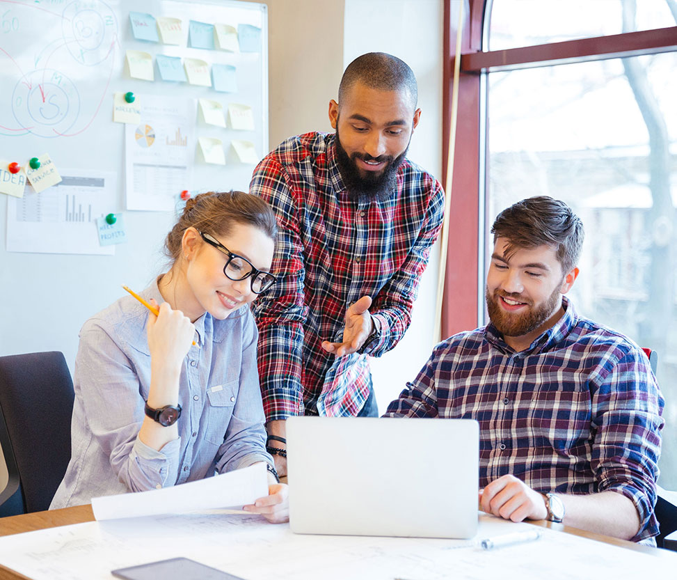 Web portal development banner- three people are talking in front of a laptop.