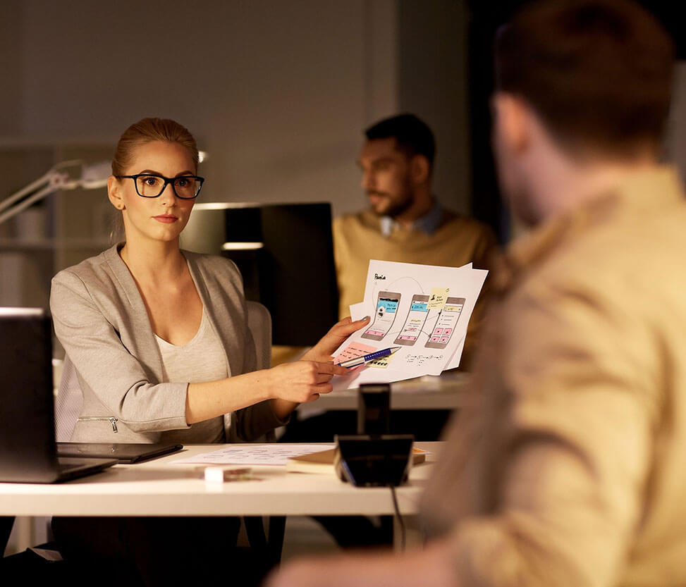 A woman is showing a mockup of a new mobile app development project to his colleague