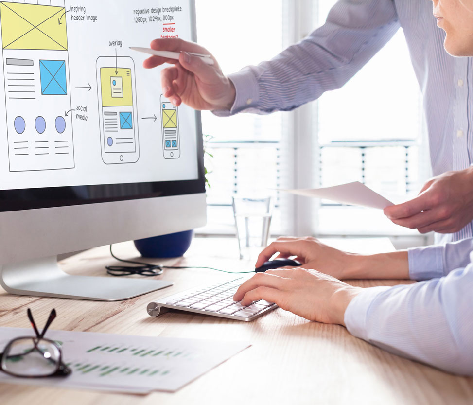 Website designer instructs his colleague on the desktop screen