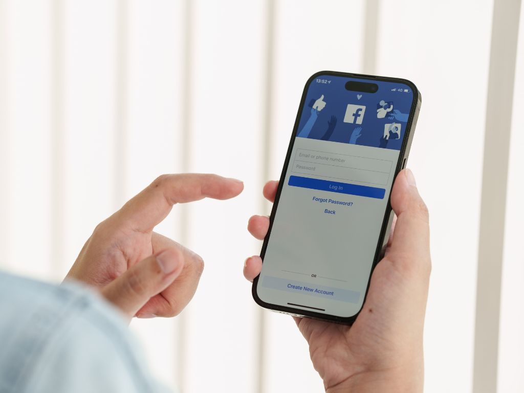 A person holds a smartphone with Facebook